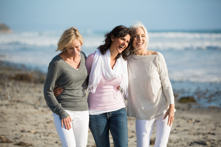 trio of happy women walking at the beach
